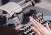 person typing using typewriter